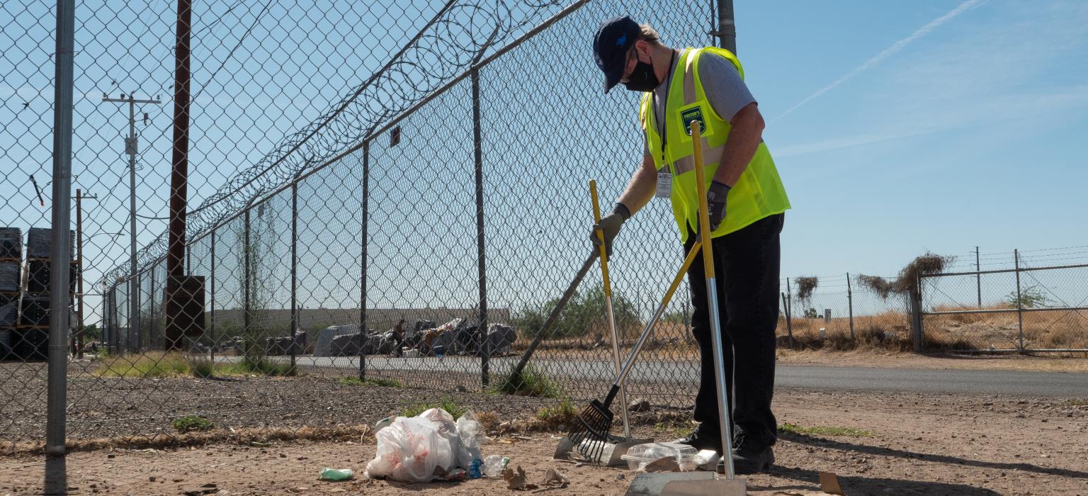 Man in yellow vest cleaning up trash