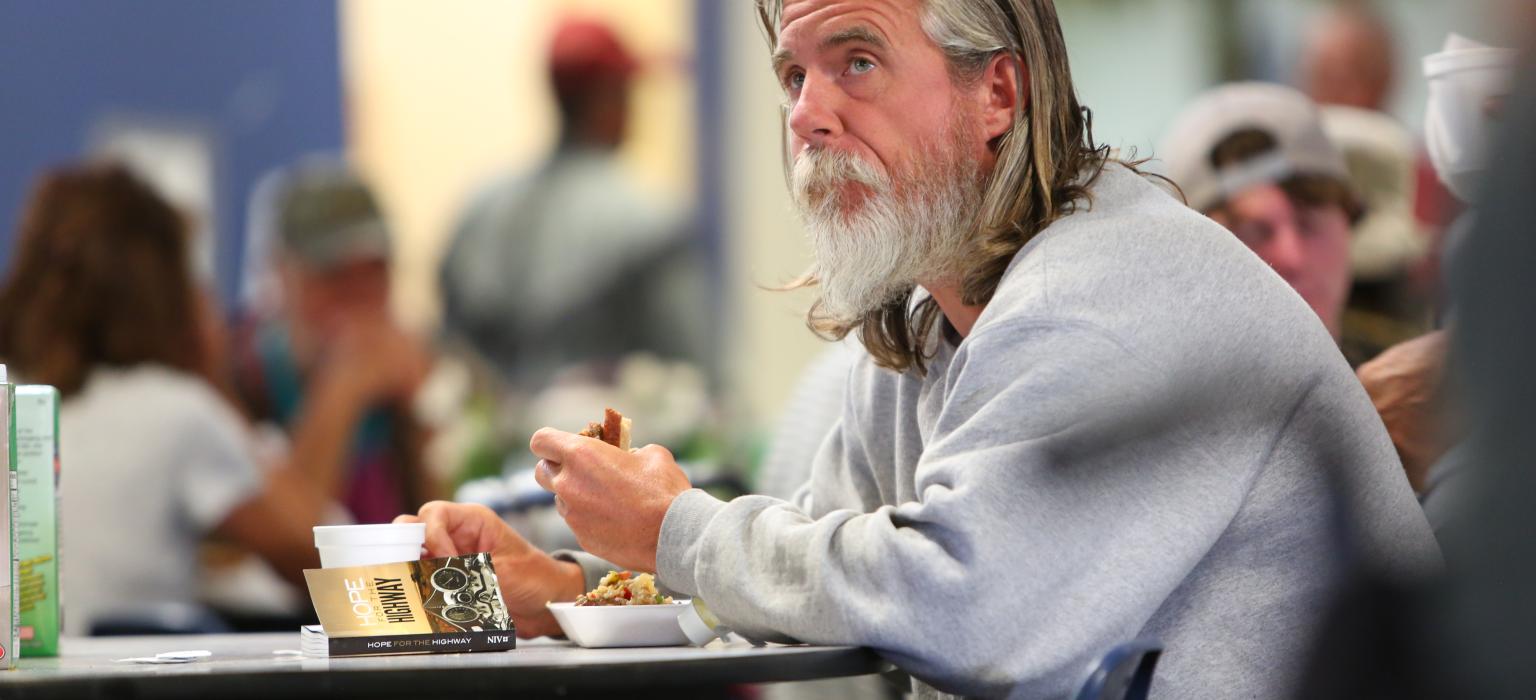 Man eating food looking off into the distance 