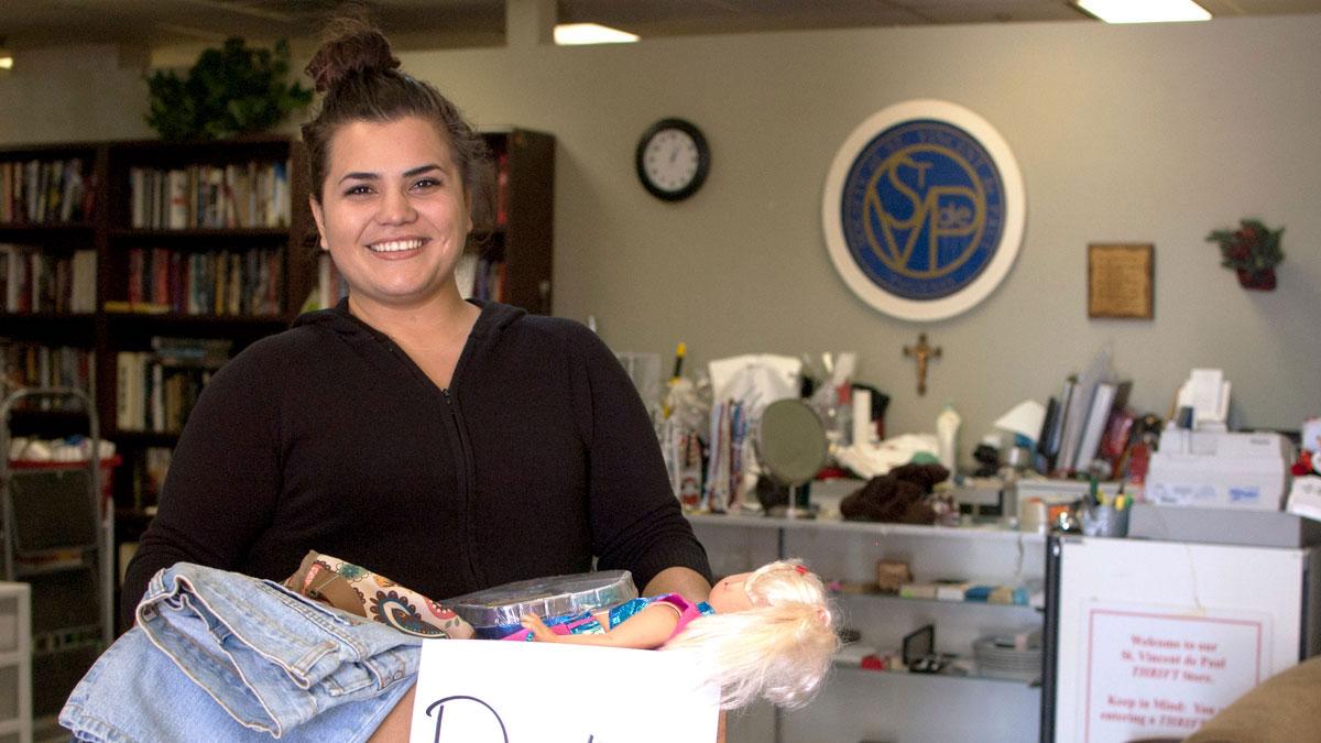 A volunteer holds a box of thrift store donations.