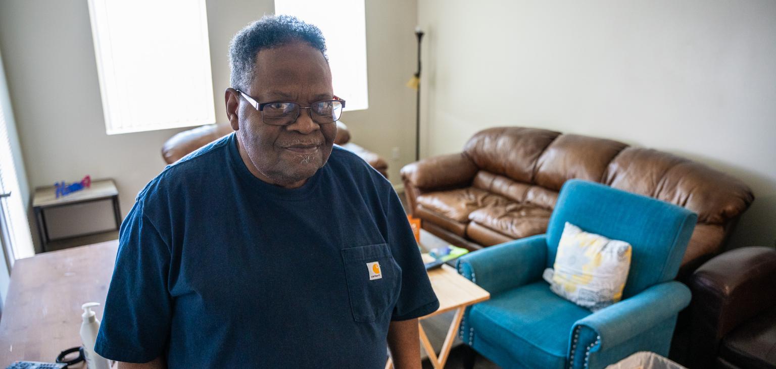 Michael Clark stands in the living room of his new apartment.