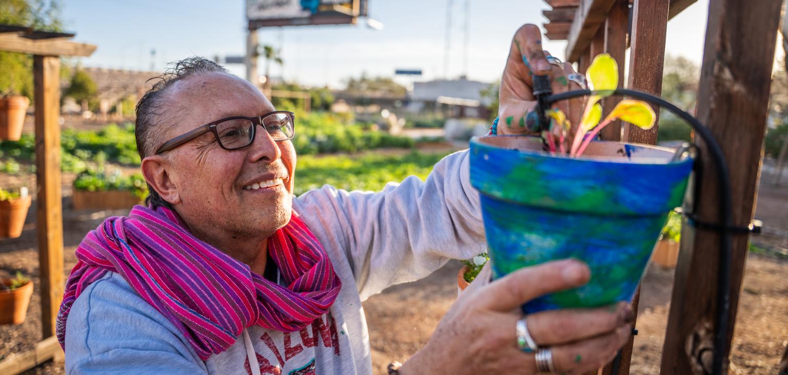 Patricio hangs up the finished potted plant at a trellis in SVdP's Rob and Melani Walton Urban Farm.