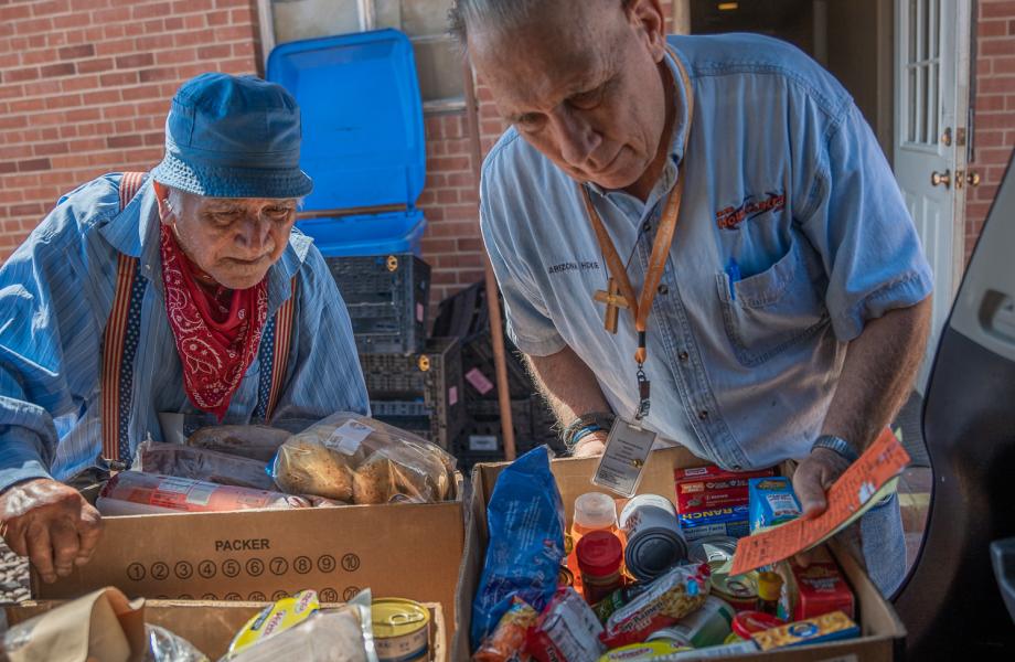 Two Vincentian volunteers load groceries in the back of a car to be delivered to families in need in their community.