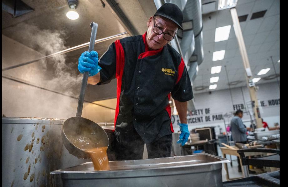 Mike ladles gravy into a tray of Turkey for Thanksgiving meals.