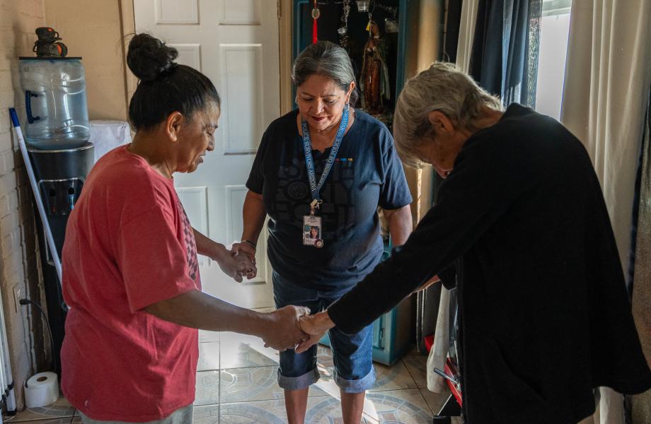 Vincentians pray with a food box recipient in her home.