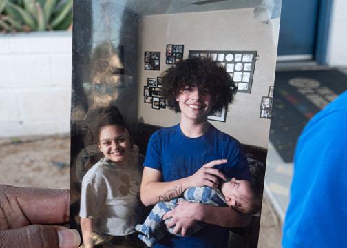 Person holding a photo of a woman and man holding a baby