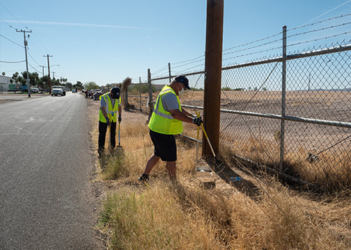 Two men cleaning up trash on the side of the road