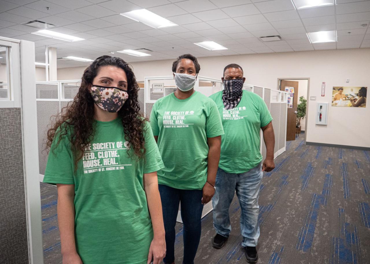 Three people in SVdP shirts standing in an office space