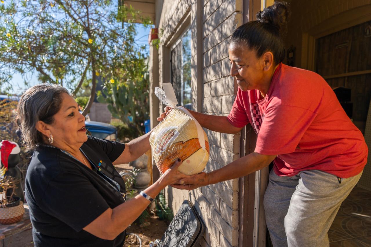 Elizabeth Rios hands Margarita her Thanksgiving turkey.